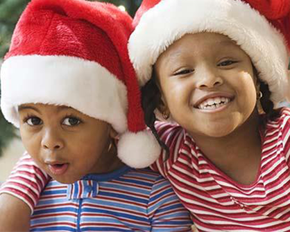 two kids wearing Santa hats smiling 